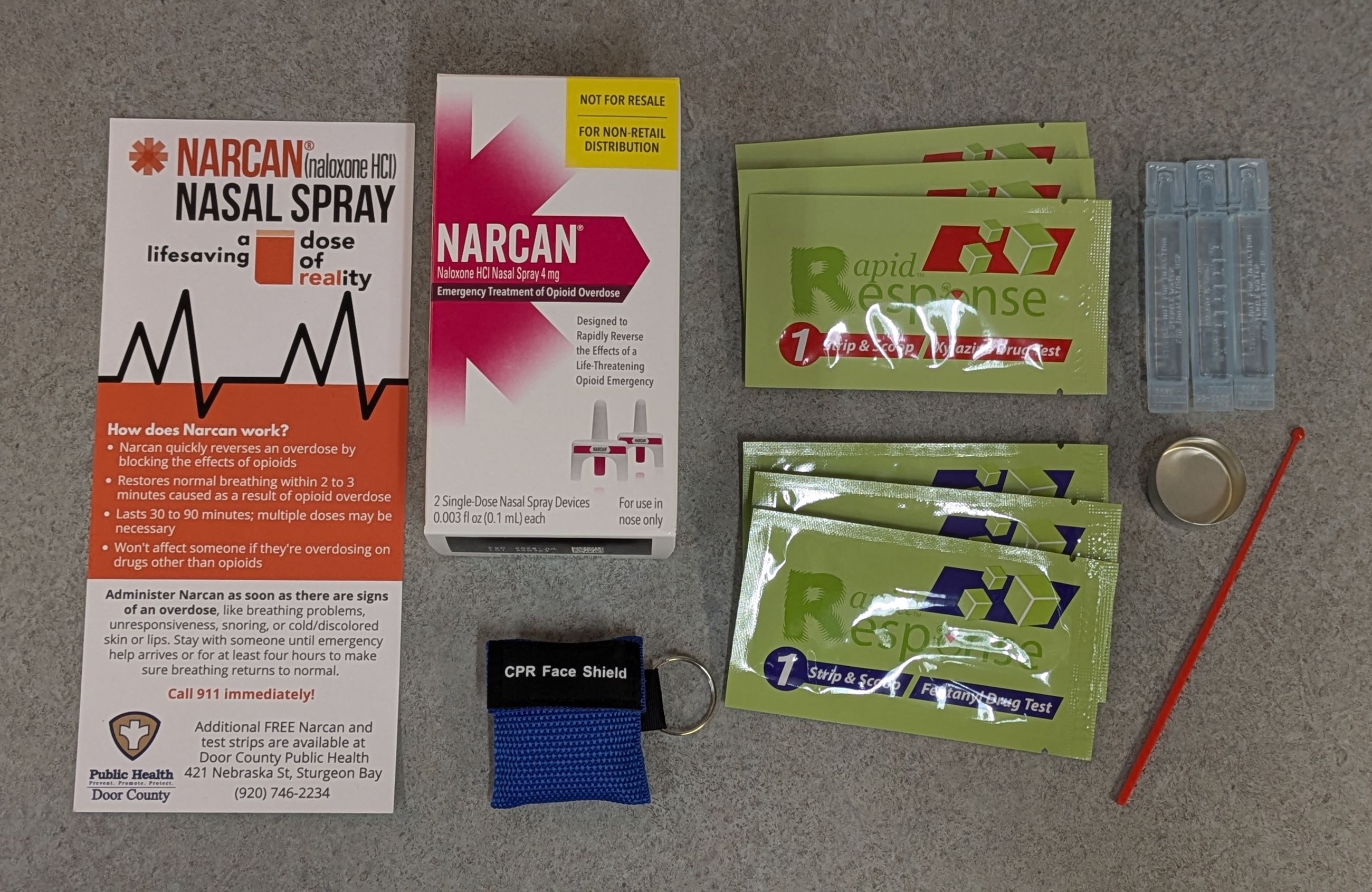 Narcan Kit Contents - two doses of Narcan, fentanyl test strips, CPR face mask in a first aid bag